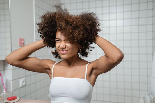 Woman lifting and shaping her curls with both hands during her bathroom haircare routine