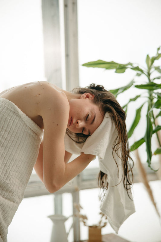 Woman holding a white towel around her wet hair after washing