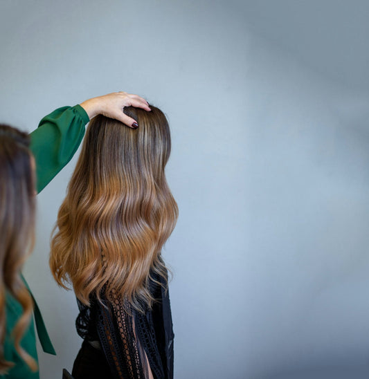 Stylist lifting long brunette hair with soft waves to show its texture